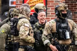 English: Border Commander Greg Bovino stands outside a South Minneapolis gas station this morning with BORTAC officers in what seemed like an effort to draw more and more people to the scene as other agents shoot high-resolution video of the crowd yelling and blowing whistles.